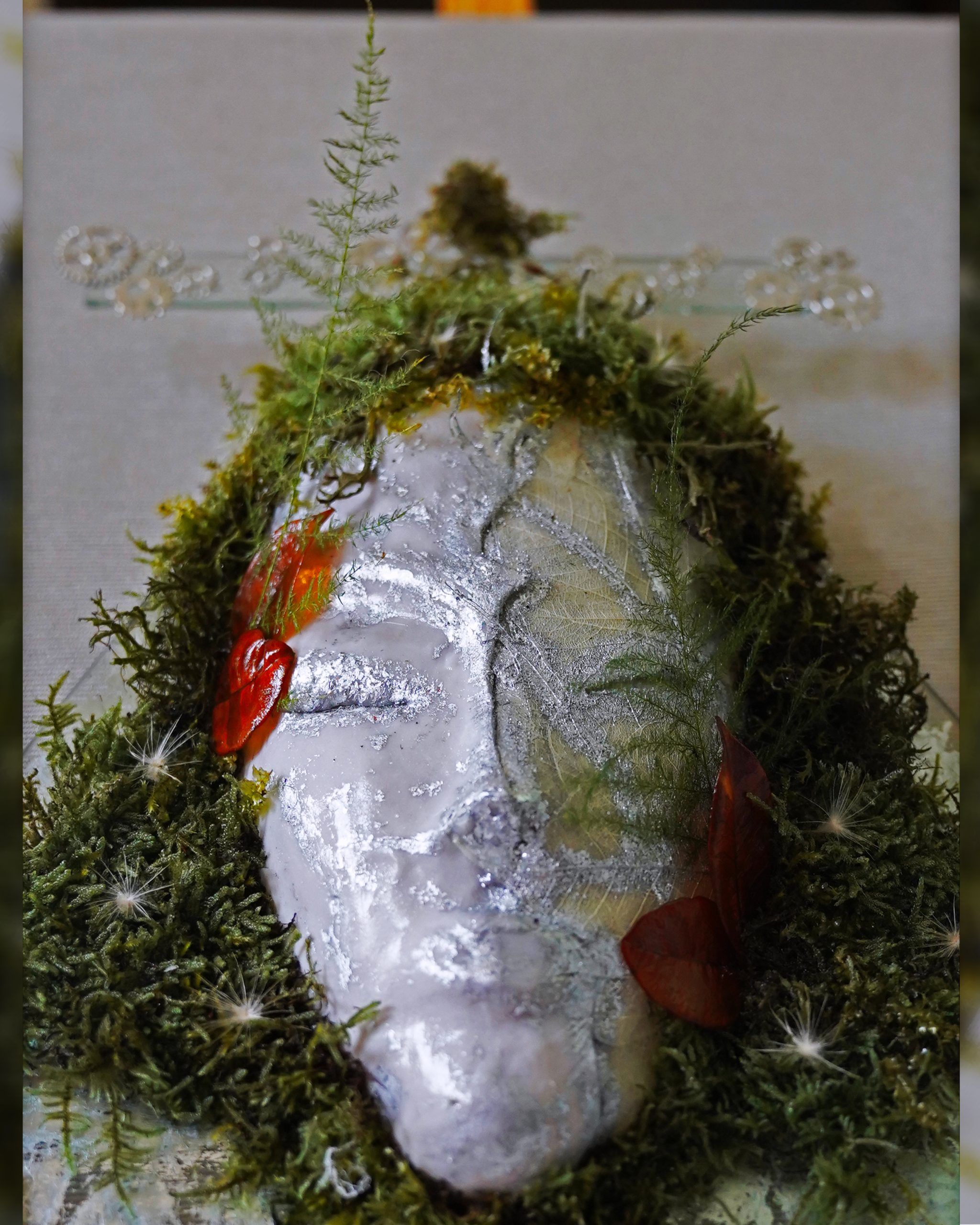 Close-up of Gemini sculpture with silver details and moss.