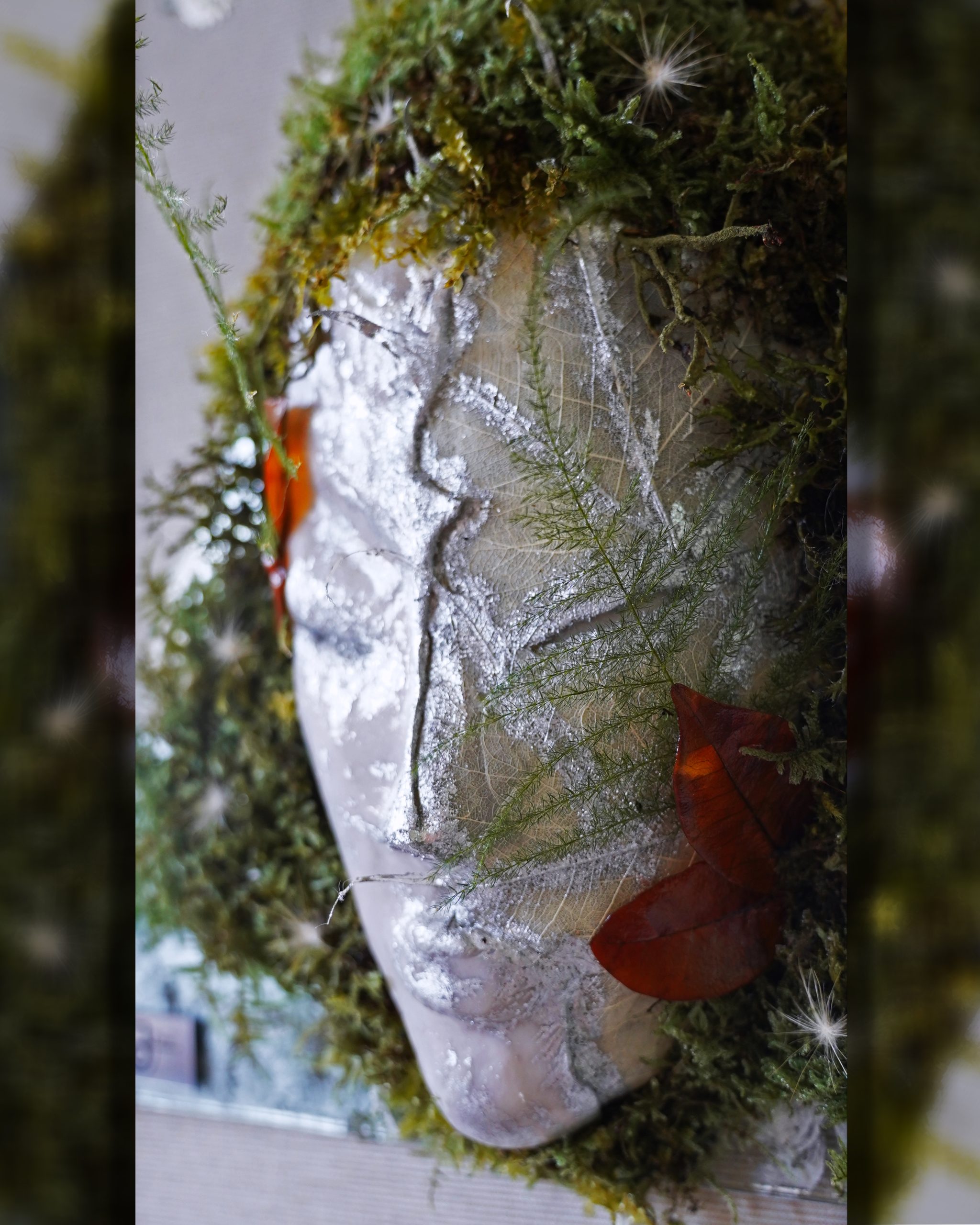 Close-up of Gemini sculpture with silver details and moss.